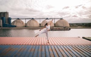 Danseuse sur un conteneur transporté par barge fluviale passant devant les silos céréaliers Simarex de Rouen.